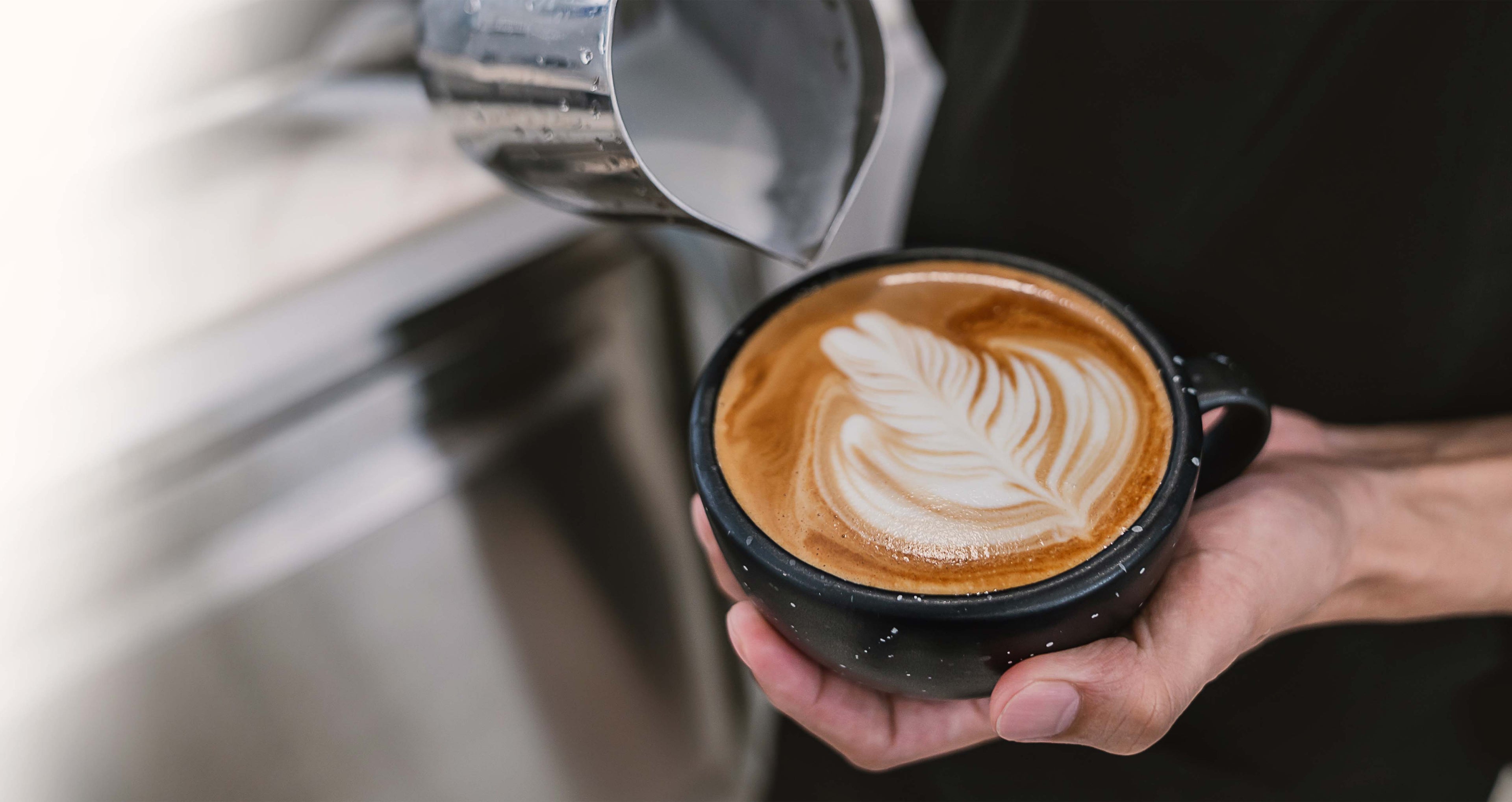 Kaffee wird mit Milchschaum in Form eines Blattes dekoriert