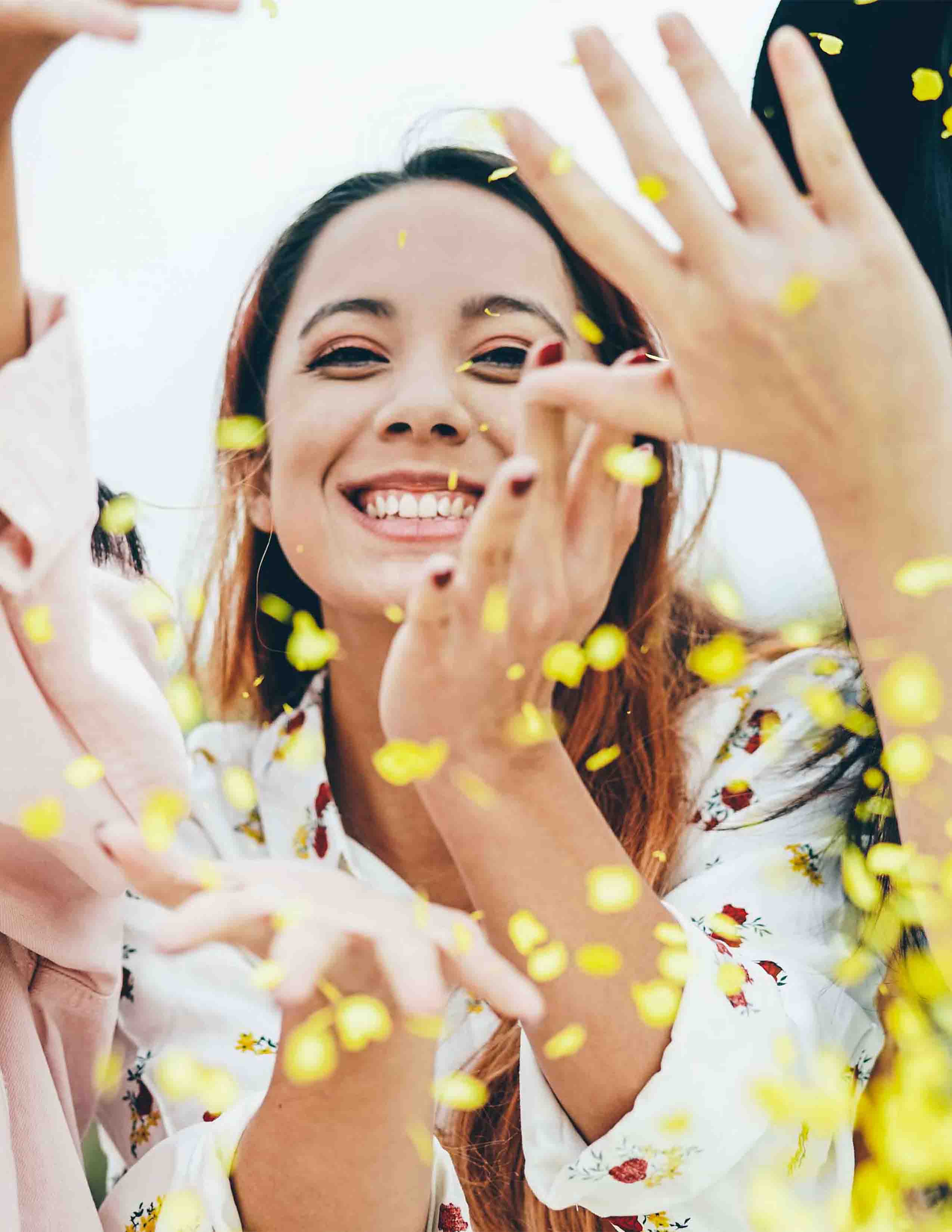 Drei fröhliche Frauen werfen gelbes Konfetti in die Luft